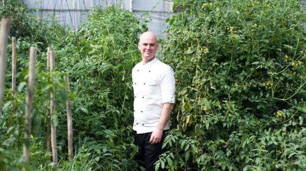 Man standing in garden, surrounded by greenery.