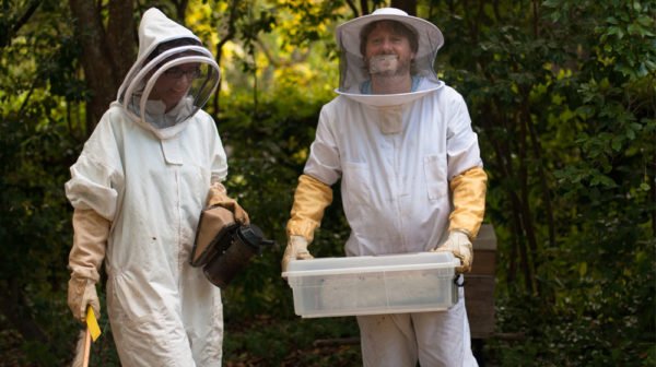 Two Beekeepers holding a Hive and posing for photo.